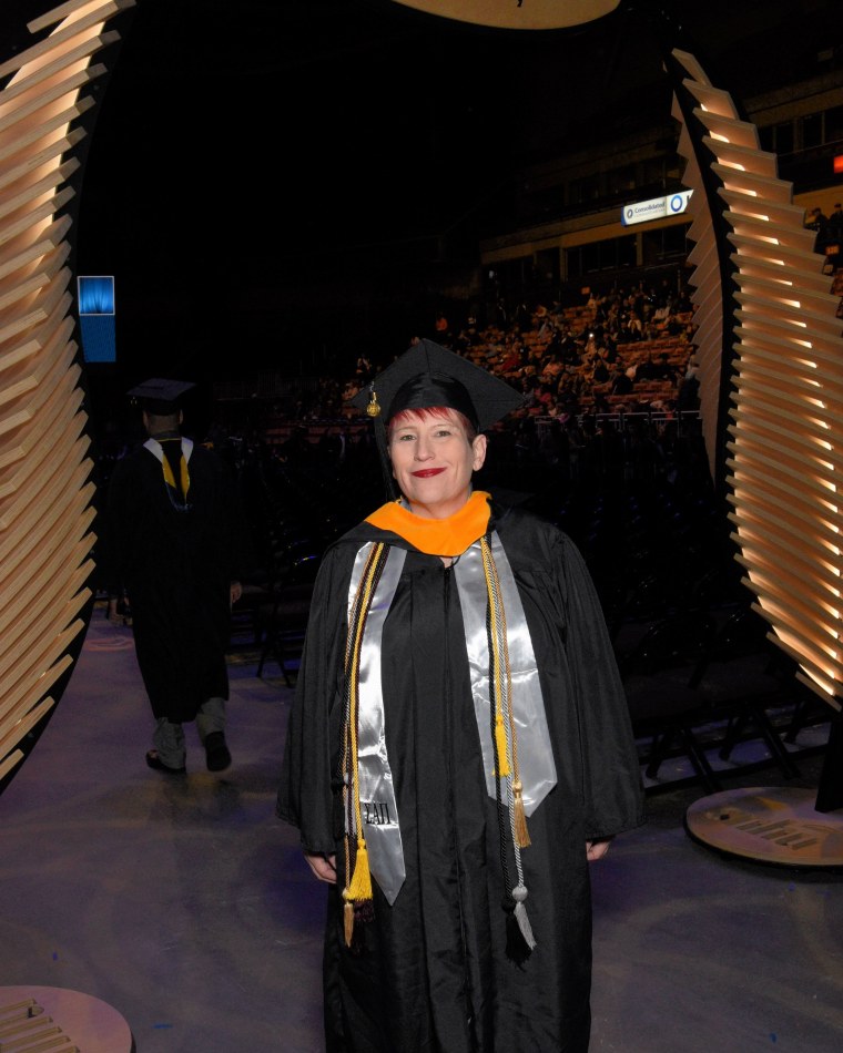 Crystal Brock walking in through the arena entrance in cap and gown