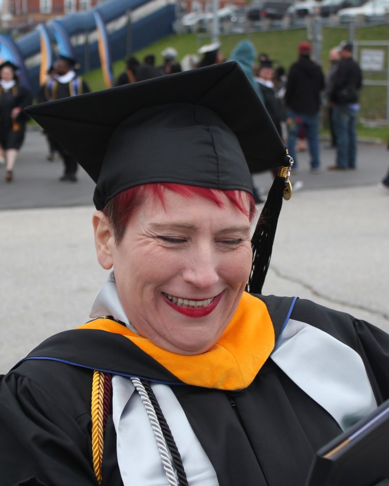 Crystal Brock laughing as she opens her diploma folder